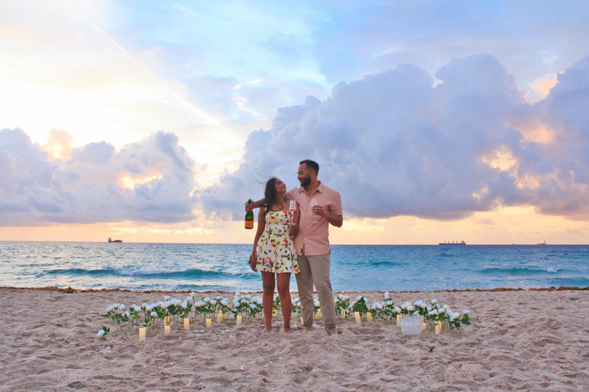 David on one knee proposing to Shriya with the sunset behind them